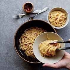 someone is holding a bowl of spaghetti in their hand