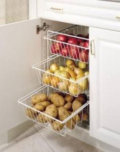 an open refrigerator door with apples, potatoes and other foods in baskets on the bottom shelf