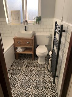 a white toilet sitting next to a sink in a bathroom under a window with a towel rack