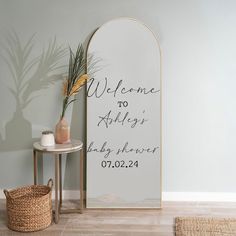 a welcome sign next to a table with a vase on it