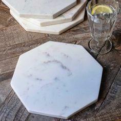 three marble coasters sitting on top of a wooden table next to glasses and a drink