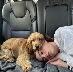 a woman sleeping in the back seat of a car with her dog