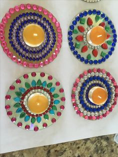 three colorful plates with candles on them sitting on a counter top next to other decorative items