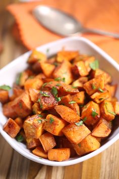 a white bowl filled with cooked potatoes on top of a wooden table