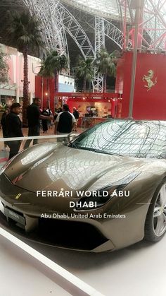 a silver sports car is on display in a showroom with people looking at it