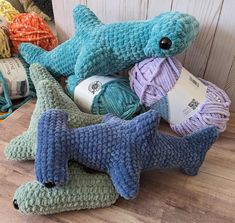 a crocheted shark stuffed animal next to balls of yarn