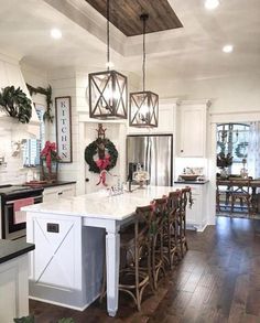 a large kitchen with white cabinets and wooden flooring, decorated for christmas time in the dining room