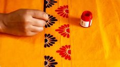 someone is sewing on an orange tablecloth with red thread and spools of thread