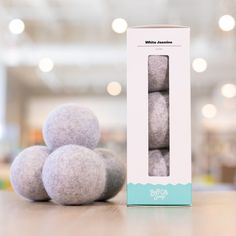 three balls of wool are sitting on the table in front of a white box with blue trim