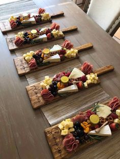 four wooden trays filled with different types of cheese and fruit on top of a table