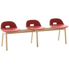 three red chairs sitting next to each other on top of a wooden table with white legs