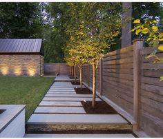 an outdoor garden with steps leading up to trees and lights on the side of it