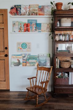 a wooden rocking chair sitting in front of a book shelf filled with children's books