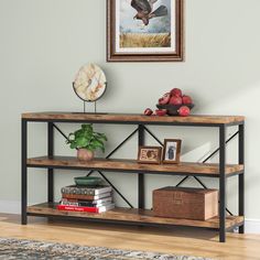 a shelf with books and pictures on it in front of a wall mounted bird painting