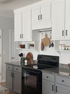 a black stove top oven sitting inside of a kitchen next to white cabinets and counter tops