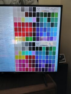 a computer monitor with multiple color swatches on it's display screen in a room