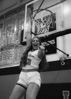 a girl is jumping in the air to dunk a basketball into the hoop with her hands