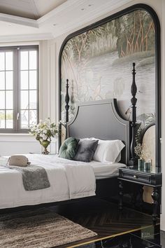 a bedroom with a bed, mirror and rug in front of a window that has a painting on the wall behind it