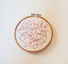 an embroidered hoop hanging on the wall that says, what do one cares? with red ink