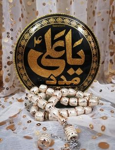 a plate with arabic writing on it next to some gold confetti and beads