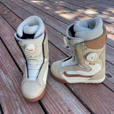 a pair of snowboard boots sitting on top of a wooden floor next to each other