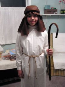 a young boy dressed in a nun costume holding an umbrella and wearing a hat with ears