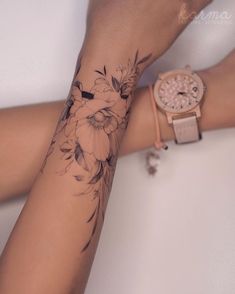 a woman's arm with flowers on it and a watch around her wrist,