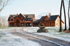 a large house in the middle of a snow covered field with a rock on the road