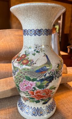 a white vase with flowers and birds painted on the side is sitting on a table