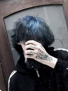 a man with blue hair and tattoos taking a selfie in front of a mirror