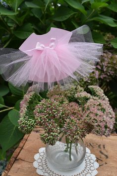 a vase filled with pink flowers on top of a wooden table next to greenery