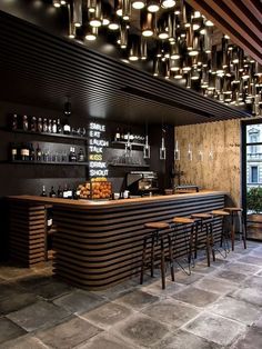 an empty bar with lots of stools and lights hanging from the ceiling above it