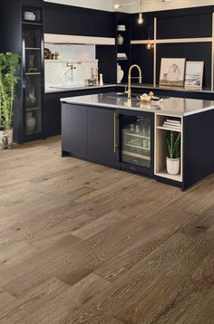 a kitchen with black cabinets and wooden floors