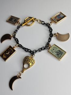 This design features a tarot motif using charms with artwork featuring a classic rider/waite feel. With a mixed metal look of black chain and golden charms it will add a dynamic touch to any look!  opened bracelet is approximately 7 in. long Witch Charm Bracelet, Rider Waite, Beautiful Lips, Black Chain, Beautiful Eyes, Charm Bracelets, Design Features, Gold Bracelet, Jewelry Bracelets