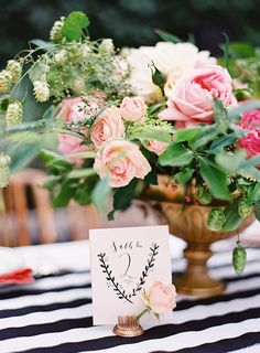 a vase filled with pink flowers on top of a black and white striped table cloth