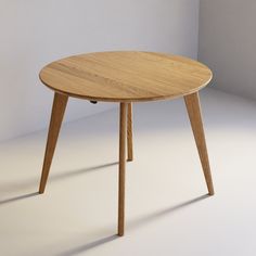 a round wooden table with two legs on an empty room floor, in front of a white wall