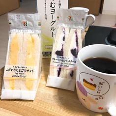 two pieces of cake sitting next to a cup of coffee on a wooden table with japanese writing