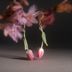 two pink and white flowers are hanging from earrings