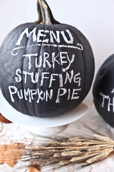 two black pumpkins with white writing on them