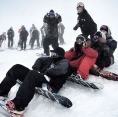 a group of snowboarders are sitting in the snow