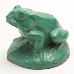 a green frog statue sitting on top of a white surface