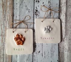 two ceramic plaques with dog paw prints on them