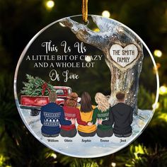 a glass ornament with three people sitting in front of a tree and the words, this is us a little bit of crazy and a whole lot of love