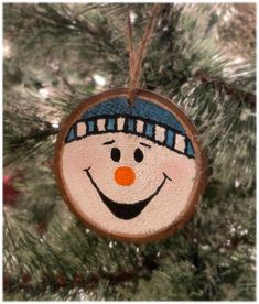 a wooden ornament with a snowman face hanging from a christmas tree branch