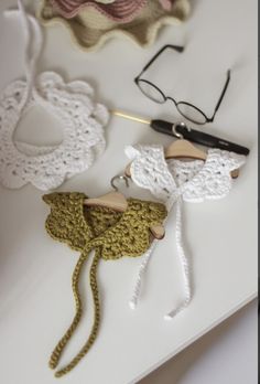 some crocheted items are laying out on a white counter top with scissors and eyeglasses