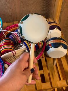 a hand holding a wooden mallet in front of several colorful baskets