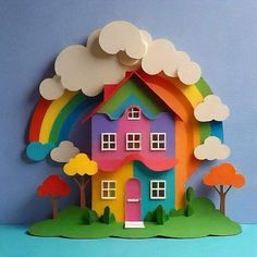 a colorful paper house with trees and clouds