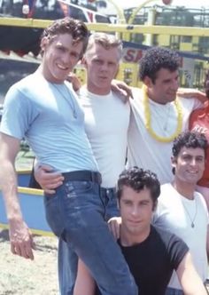 a group of men standing next to each other in front of a carnival ride at a fair