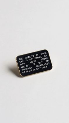 a black and white pin that says the quality of your life