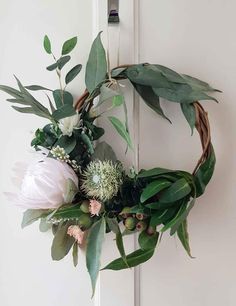 a wreath with flowers and greenery hanging on the front door for an easy diy project